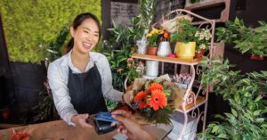 Small flower shop owner uses credit card reader to take payment.