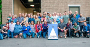 NBM team celebrating together in front of their warehouse.